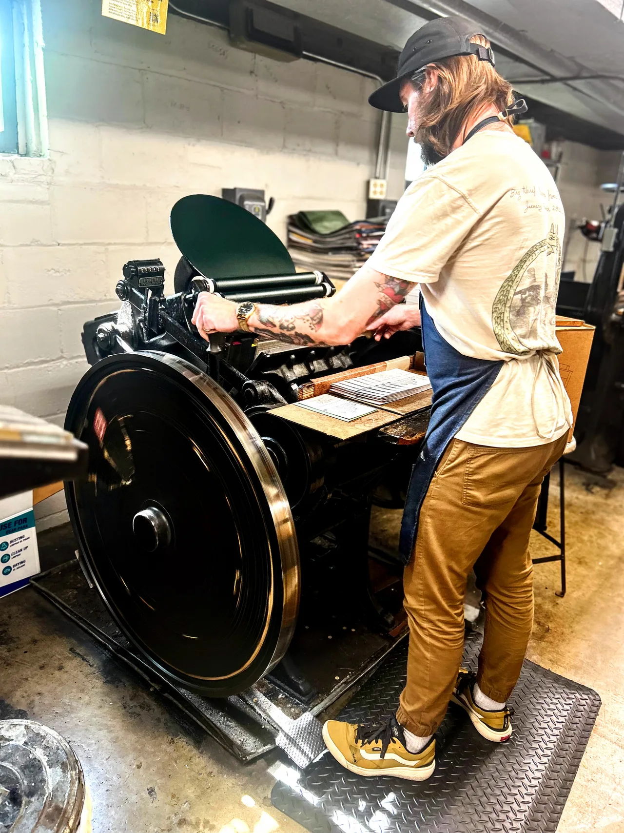 An employee printing an advertisement using an antique printing press at Bay View Printing Company.