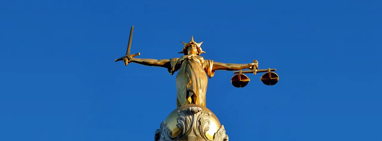 Une statue de Lady Justice, une personnification de la justice, souvent représentée avec une balance et une épée, symbolisant l'équité et l'impartialité de la loi, un concept remis en question par le biais algorithmique.